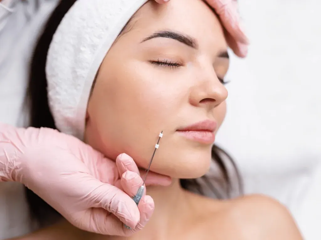 Gloved hands holding a syringe beside a woman’s face