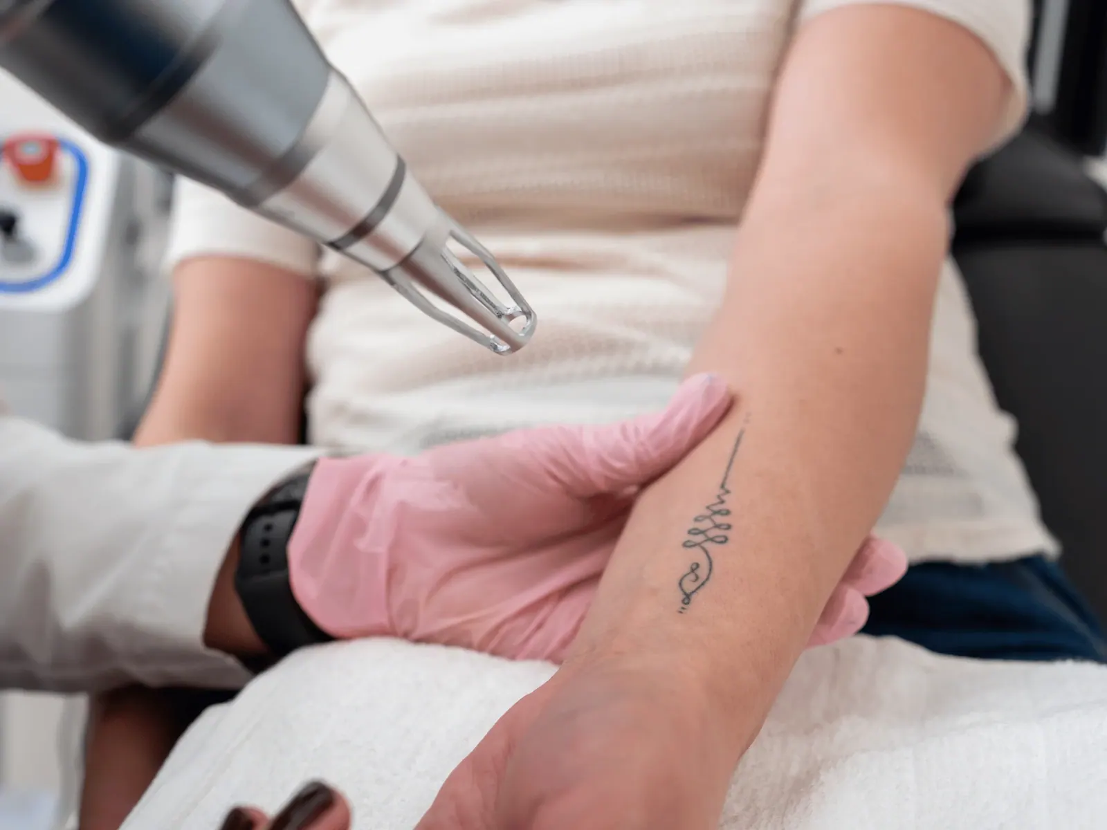 Treatment device held above a tattooed forearm